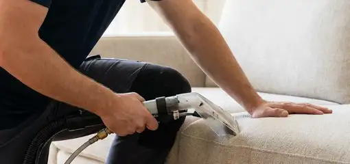 Professional upholstery cleaner deep-cleaning a fabric sofa with a handheld extraction tool, Jersey City, NJ.